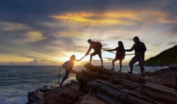Hikers helping each other on an outdoor team-building adventure