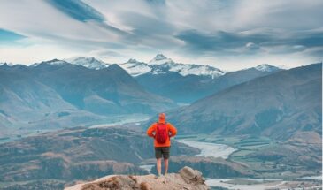 Man on a trail top watching majestic scenery on an adventure in New Zealand