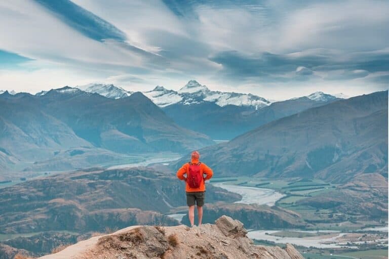 Man on a trail top watching majestic scenery on an adventure in New Zealand
