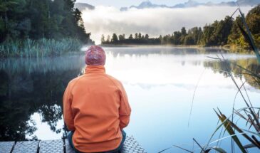 Man hiking in the New Zealand outdoors, resting by a lake.